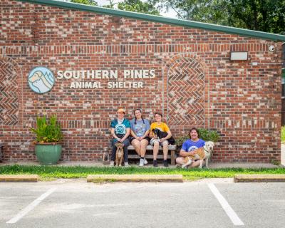 Four people and three dogs outside of Southern Pines Animal Shelter